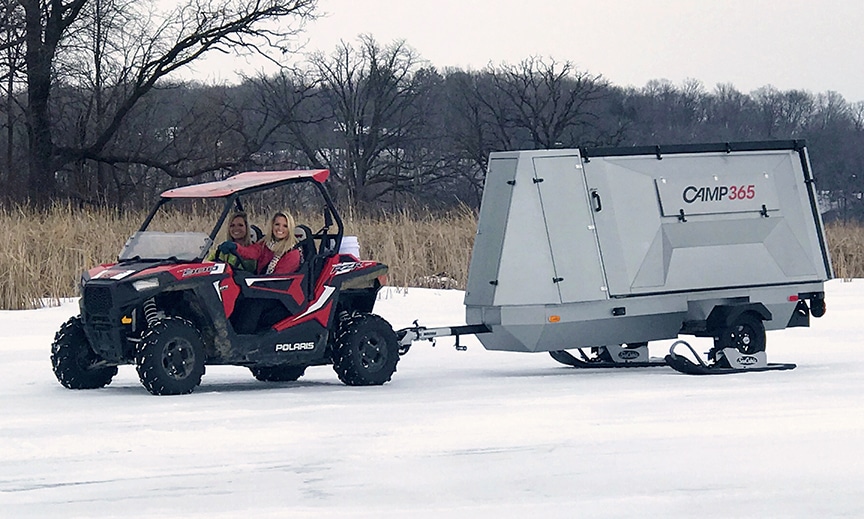 An off-road vehicle pulling the trailer on ice in winter.