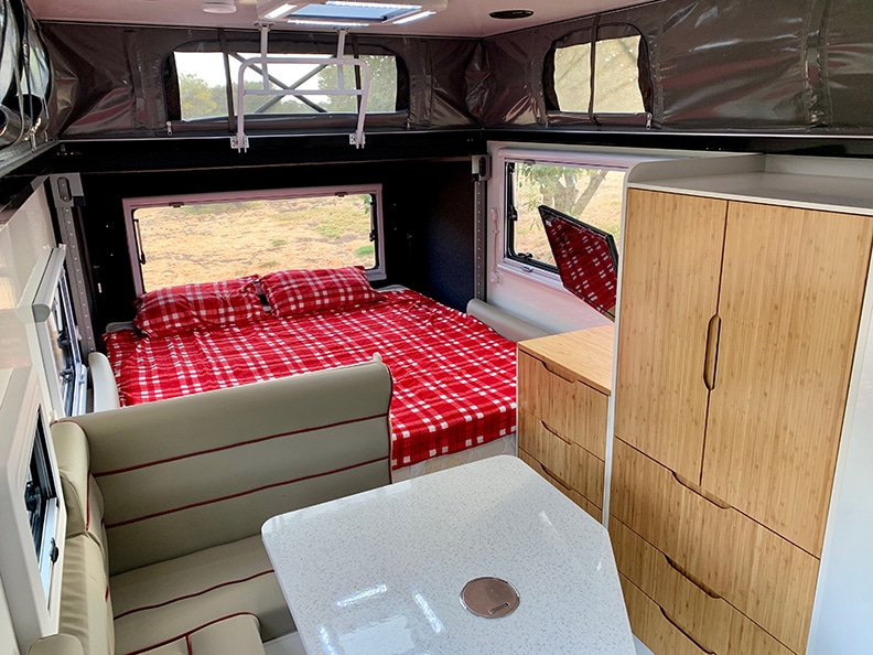 Red plaid cover and pillows on king bed inside trailer