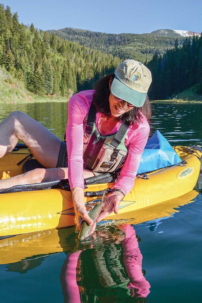 The author releases a rainbow trout she caught on glassy Sylvan Lake in the White River National Forest.