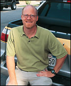 Man sitting on bumper of car wearing green polo shirt