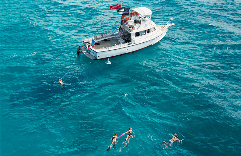 A dive boat on the water surrounded by several snorkelers.