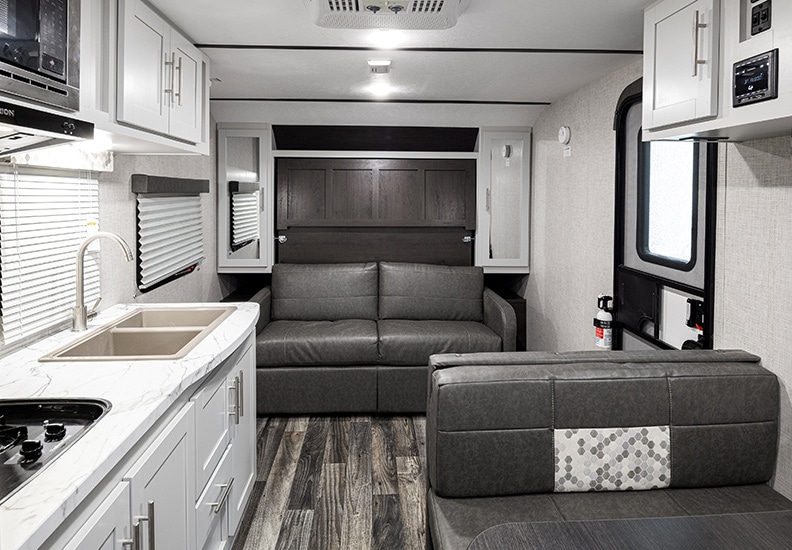 Gray Murphy bed in couch position with white cabinets on either side.