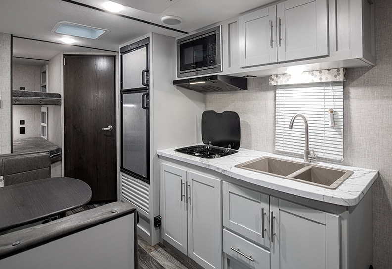 White cabinets in the kitchen with stainless refrigerator and microwave.