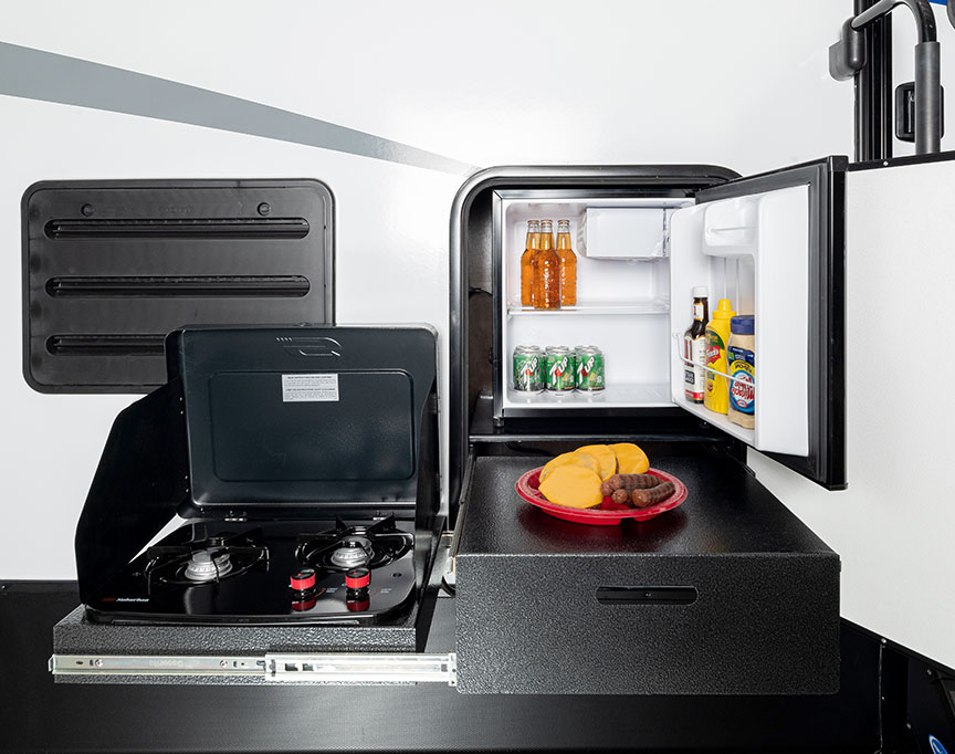 Exterior kitchen of Passport trailer with fridge door open.