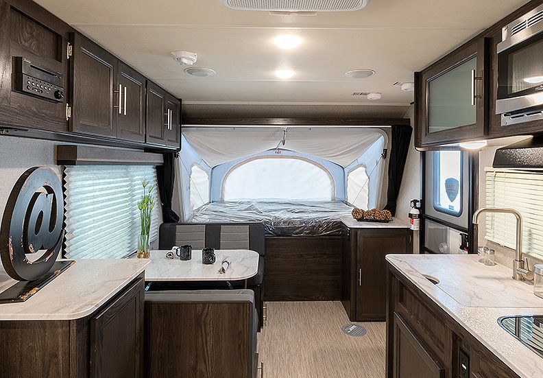 Inside the Kodiak Cub 1795 trailer with a view of the kitchen's light colored countertops and front tent extension.