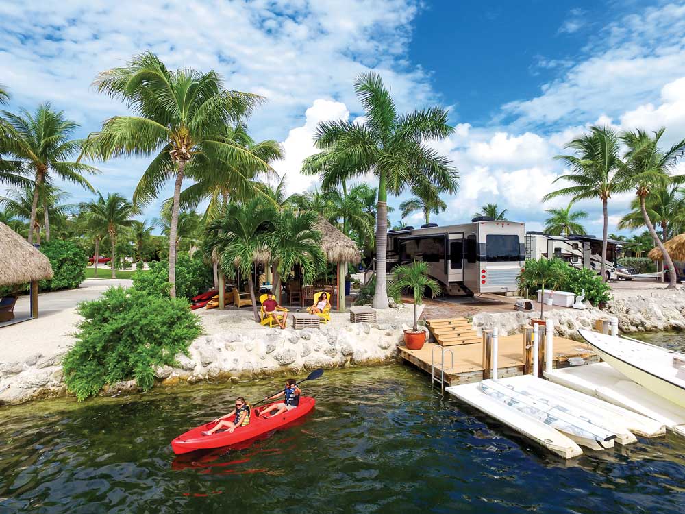 Beautiful dock in Lower Keys with palm trees and red kayak with people 