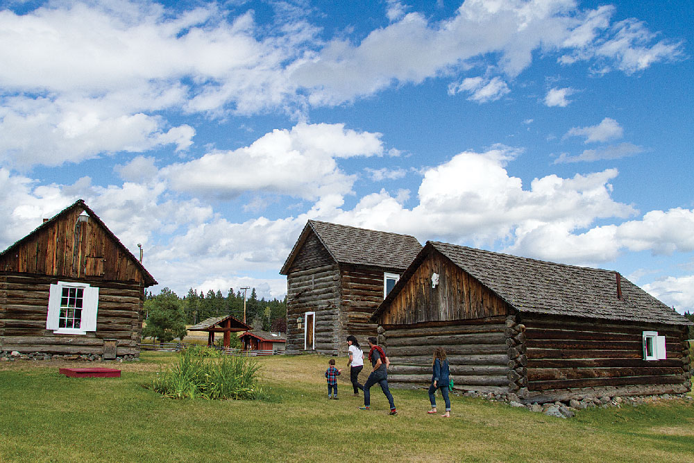 A family explores the 108 Mile House Historic Site’s log structures and exhibits. 