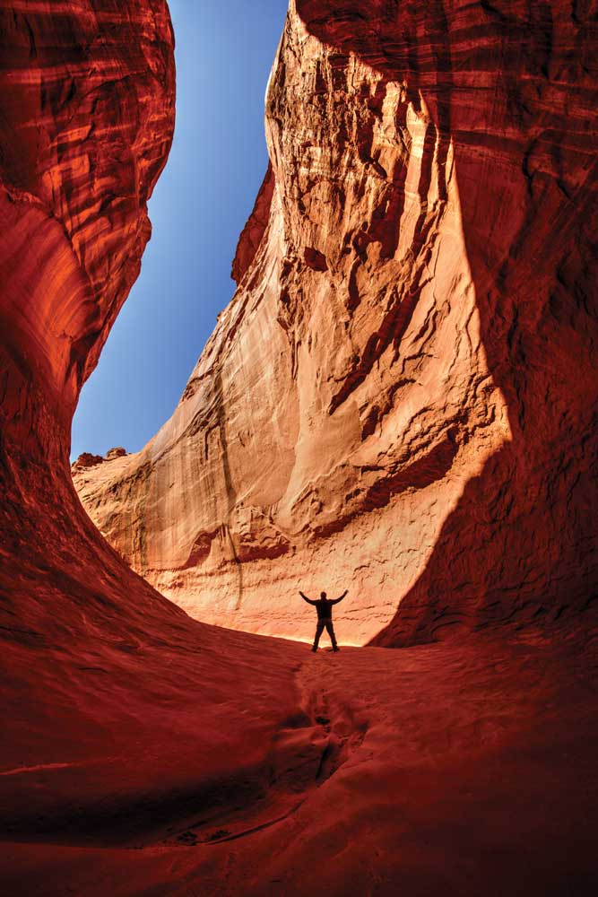 Photo of person from a distance standing in rock formation to illustrate the photographic technique of scale
