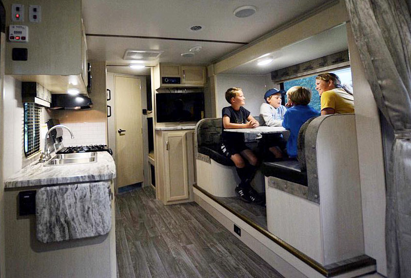 Family seated at dinette inside RV trailer