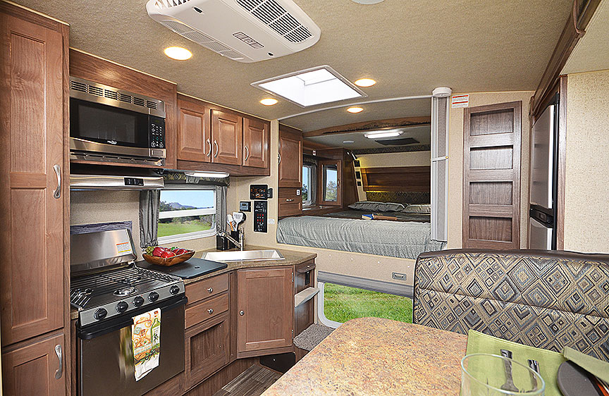 Interior of 990 camper with bed in background and kitchen in foreground.