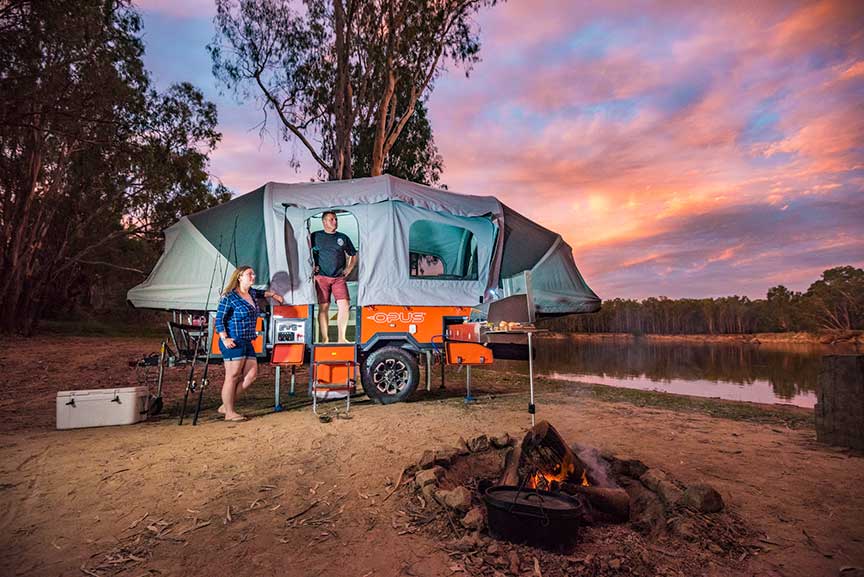 Opus Camper with roof extended at campsite with sunset in background.