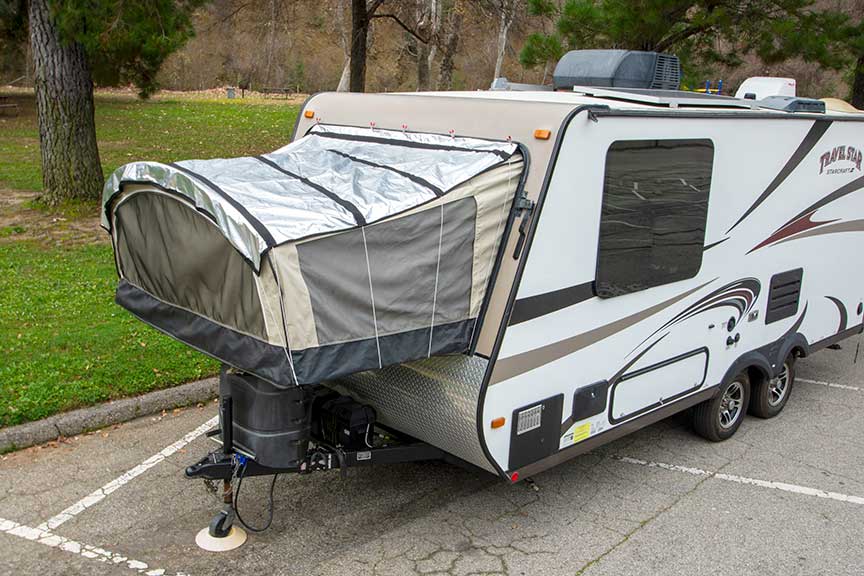 White TravelStar hybrid trailer with PopupGizmos cover on front bunk-end at grassy park