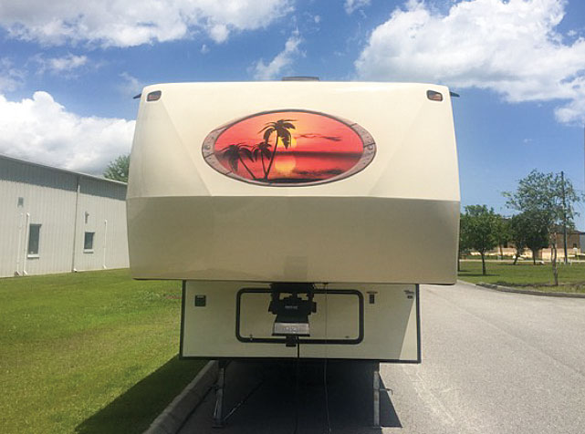 Fifth-wheel with vinyl wrap and oval sunset decal on front cap.