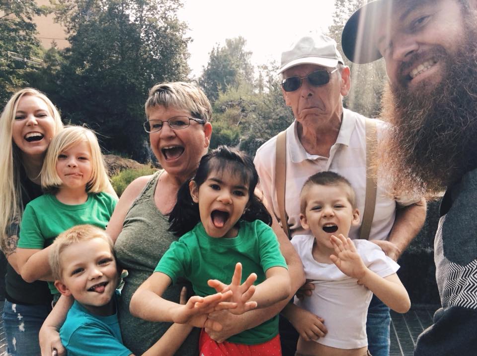 Family of parents, grandparents and children smiling at camera outside