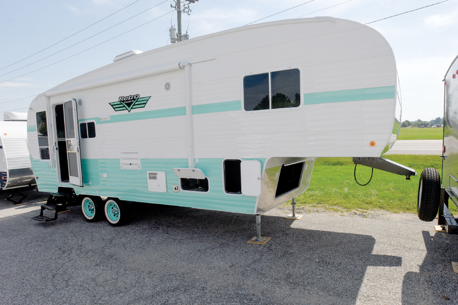 White and light turquoise travel trailer parked with door open