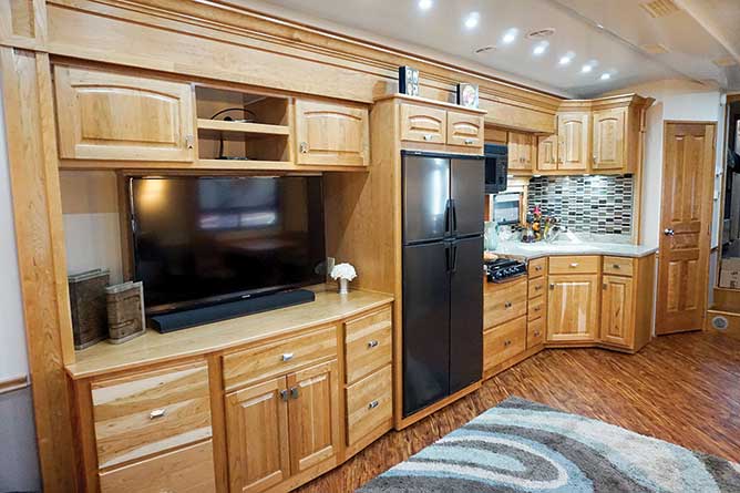 Wooden cabinets with tv and kitchen in large motorhome