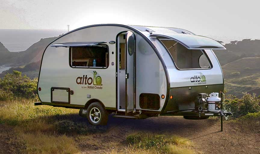 Silver Safari Condo Alto teardrop trailer in front of body or water.