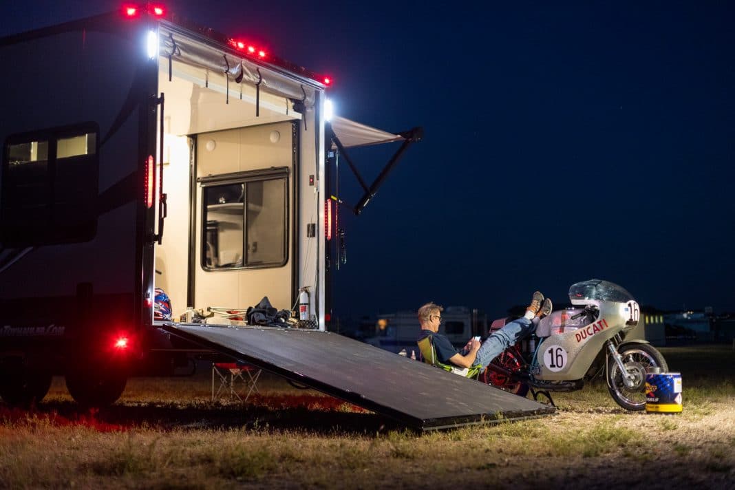 Night scene of ATC toy hauler and author John L. Stein with his feet resting on a silver motorcycle