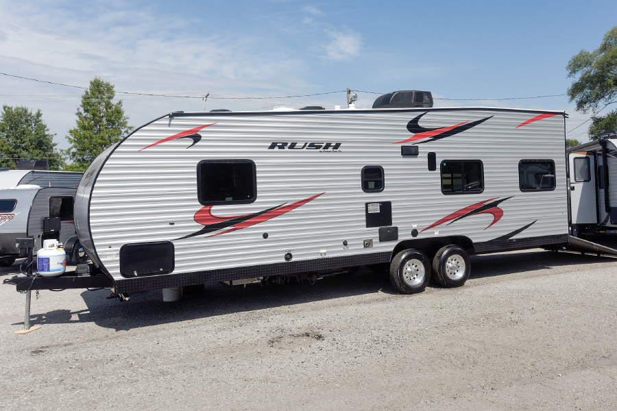 White fifth wheel with red and black designs parked