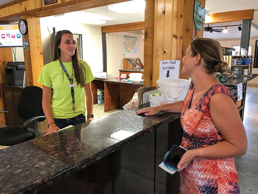 Woman wearing green shirt talking to woman behind counter