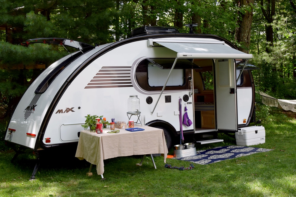 White Little Guy teardrop trailer with table in front on grass