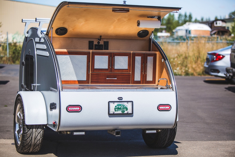 White teardrop camper with door open in parking lot