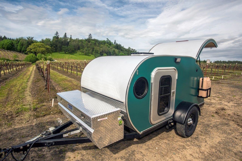 Teal teardrop camper with back door open at vineyards