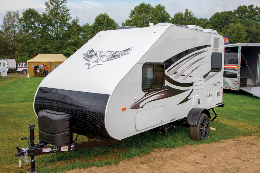 Small white Falcon travel trailer parked on grassy area