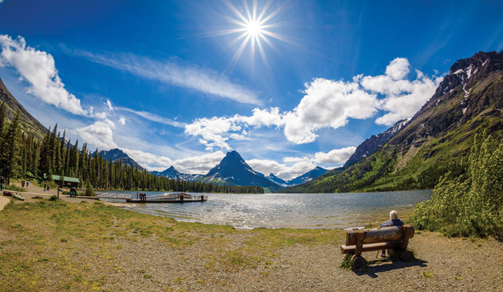 Person sitting on park bench looking over Two Medicine in Waterton Lakes National Park