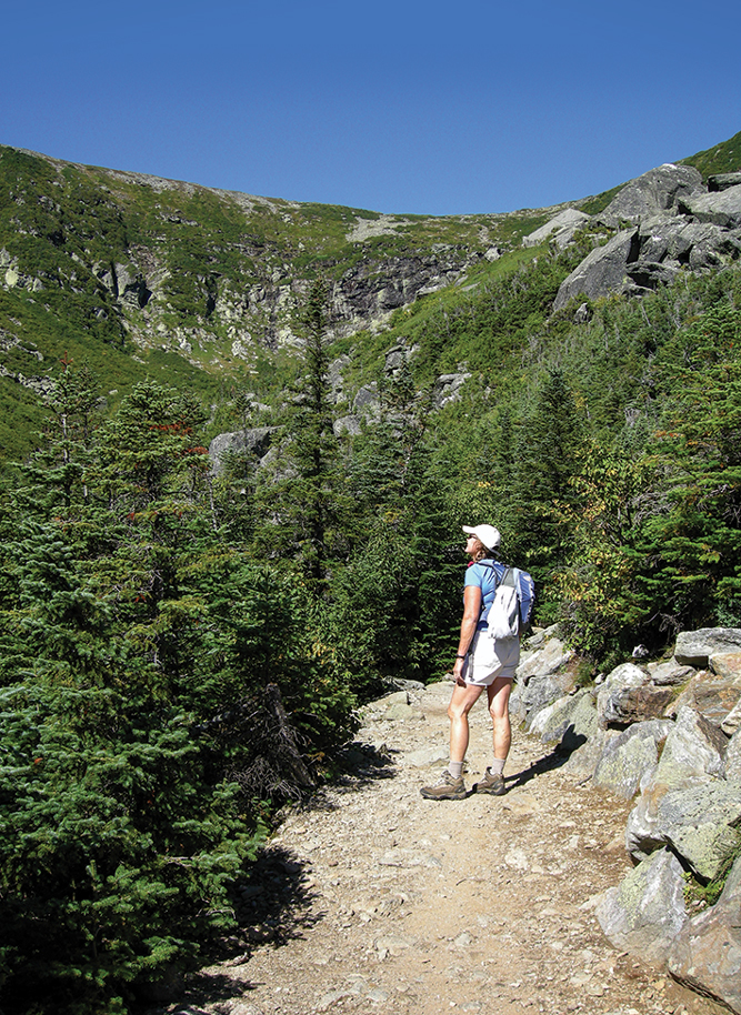 A hiker ogles Tuckerman Ravine on Mount Washington, a renowned hike-up ski slope that turns into an impressive cliff after the snow melts.
