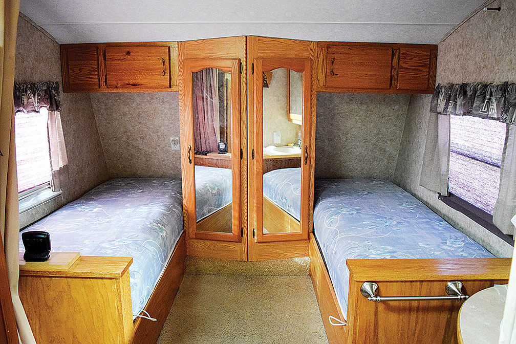 Twin beds in RV with mirrored closets between them