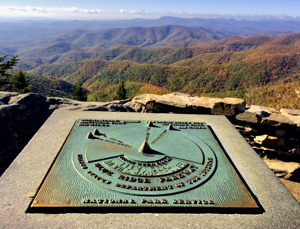 Rusty green sundial on concrete slab overlooking canyon staying Devils Courthouse, along Blue Ridge Parkway