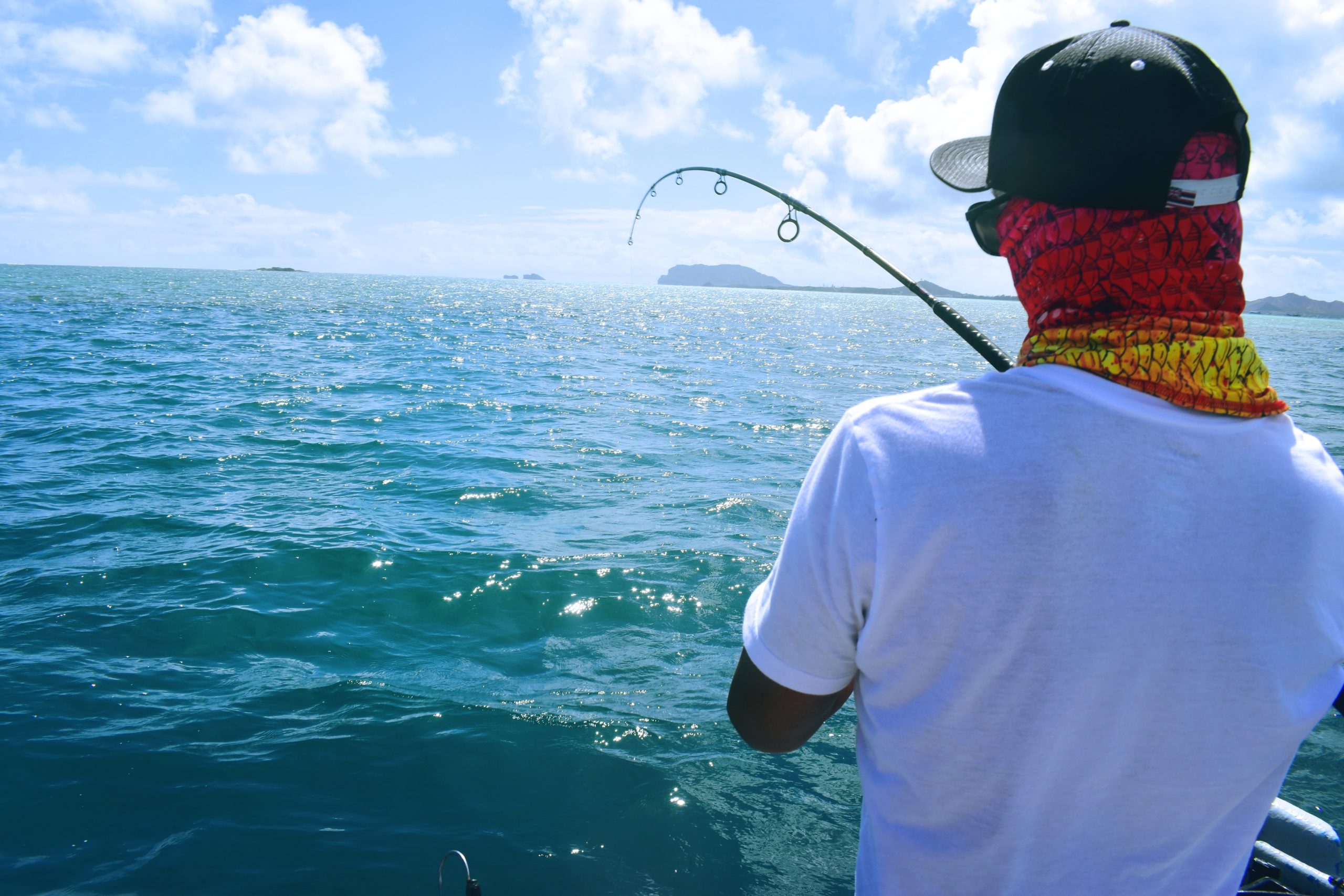 Young man wearing red bandana and baseball hat fishing at Kaneohe Bay