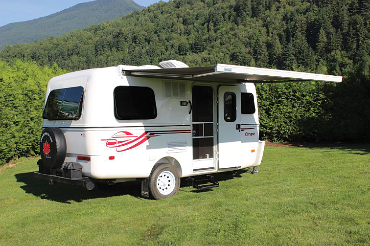 White Escape travel trailer with awning open parked on grass