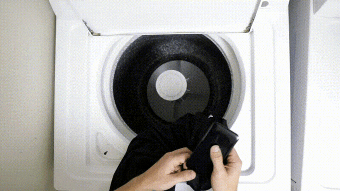 Man putting shirt in washer and closing lid