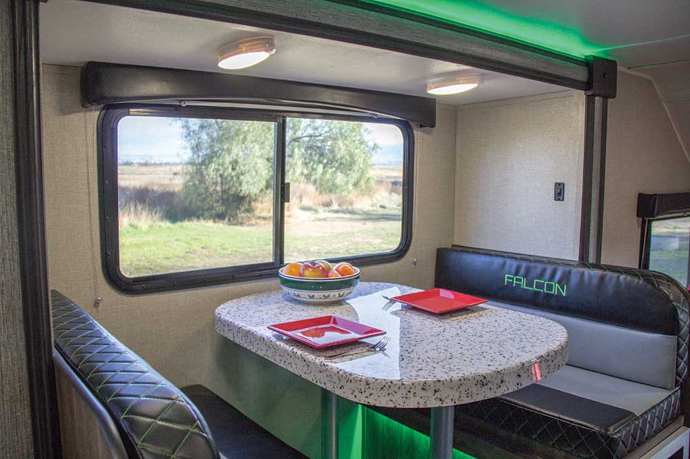 Individually controlled LED light fixtures are positioned throughout the interior. The dinette is accented with green LEDs above and below and a large sliding window. 