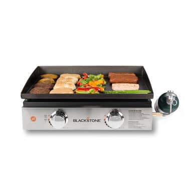 Blackstone 22” Tabletop Griddle holding sausages and burger patties