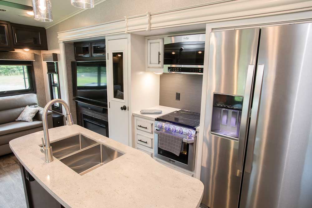 contemporary modern interior of RV with kitchen island and steel refrigerator