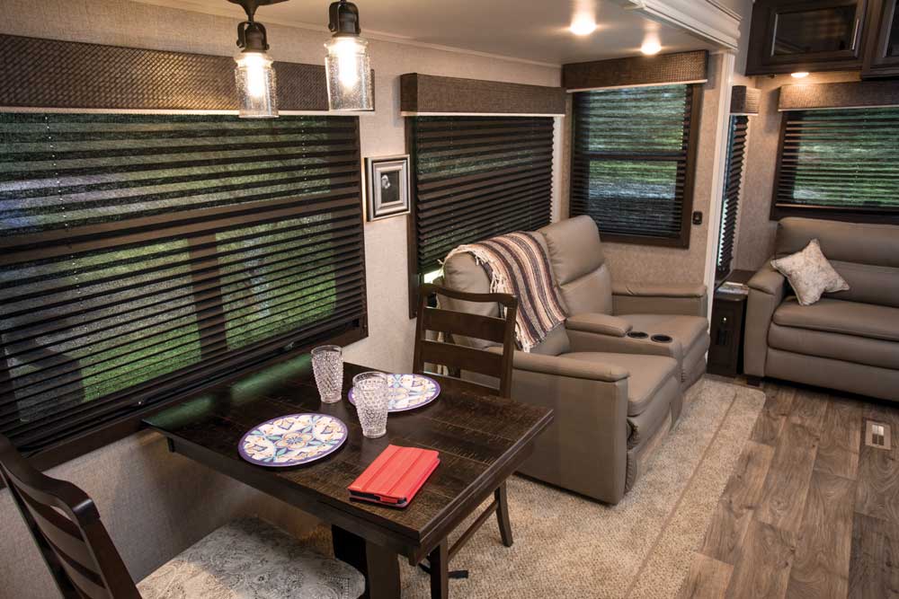 Reclining theater seats opposite 50-inch TV and a dinette with storage in RV