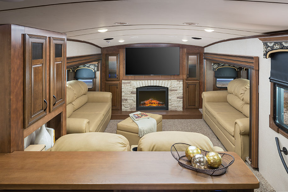 A 60-inch LED TV, electric fireplace and stone-look hearth form the centerpiece of the forward living room, which features couches in opposing slide-outs. A third couch with dual theater seats faces the high-definition TV.