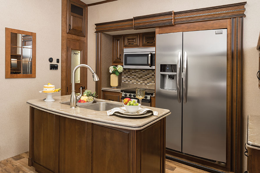 Residential touches include a gooseneck faucet above twin stainless-steel sinks in the kitchen island.