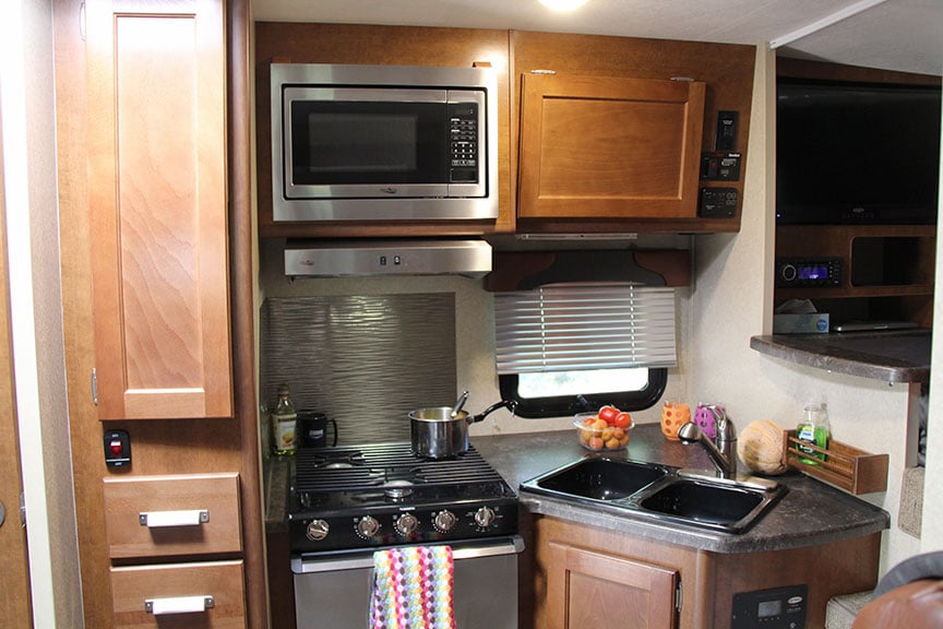 Lance 855s camper kitchen with stainless-steel appliances and black sink.
