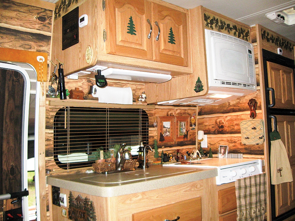 This log cabin makeover is all in the details. From the evergreens on the cabinet doors to the pinecone wallpaper inlay of the kitchen.