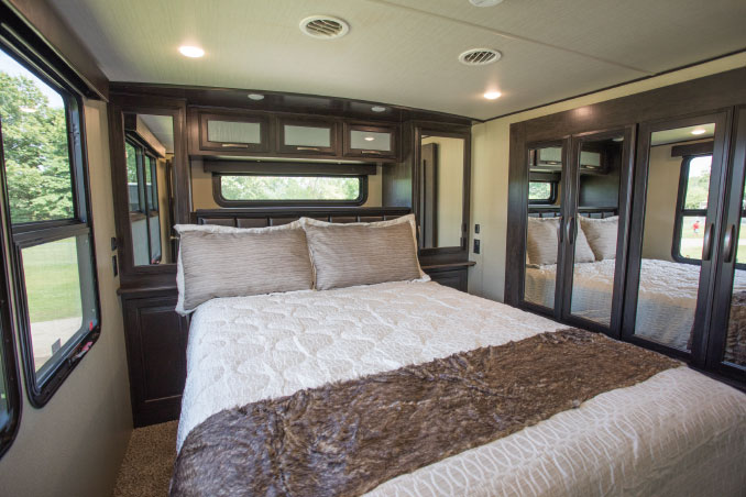 Windows and closet surrounding made bed in RV