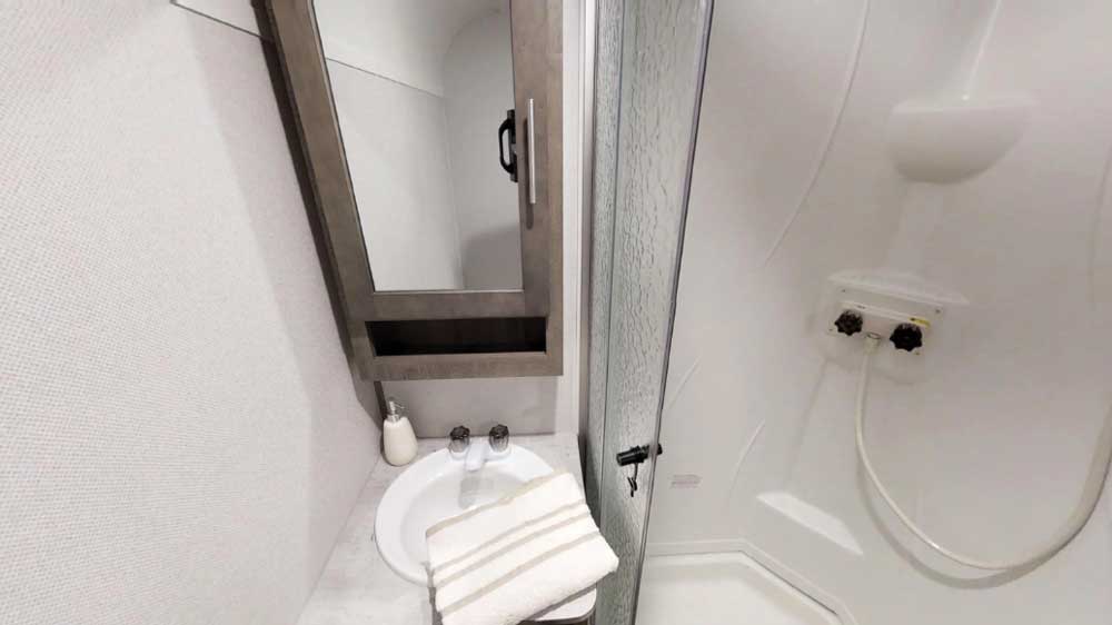 There’s no sacrificing comfort and convenience in the bathroom, which sports a roomy radius shower and a sink with a mirrored medicine cabinet above it.