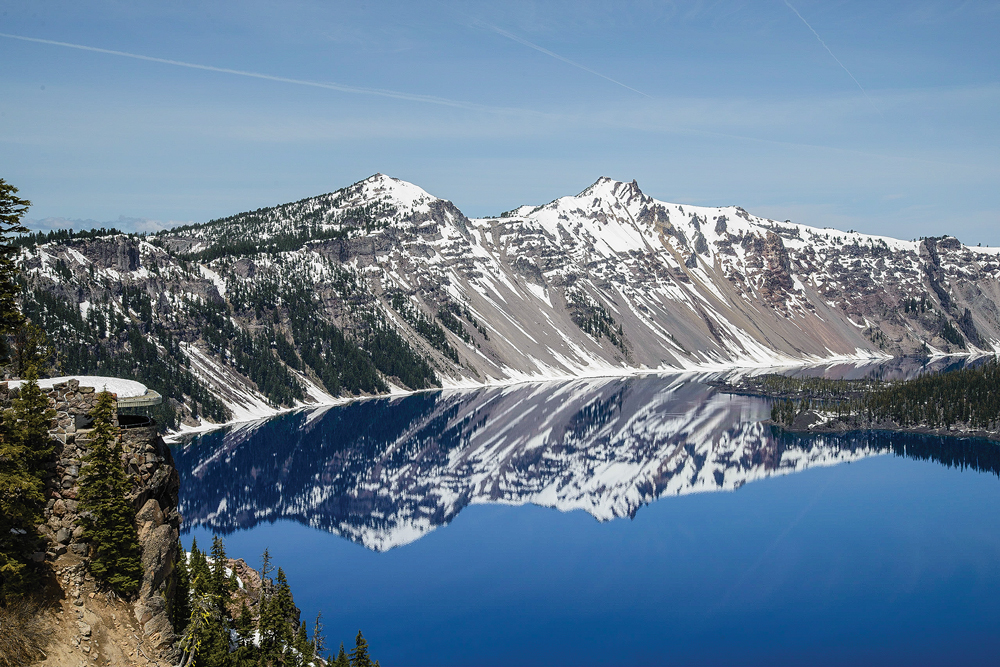 Vivid blue Crater Lake mirrors the rim’s sparkling snow and pine trees.