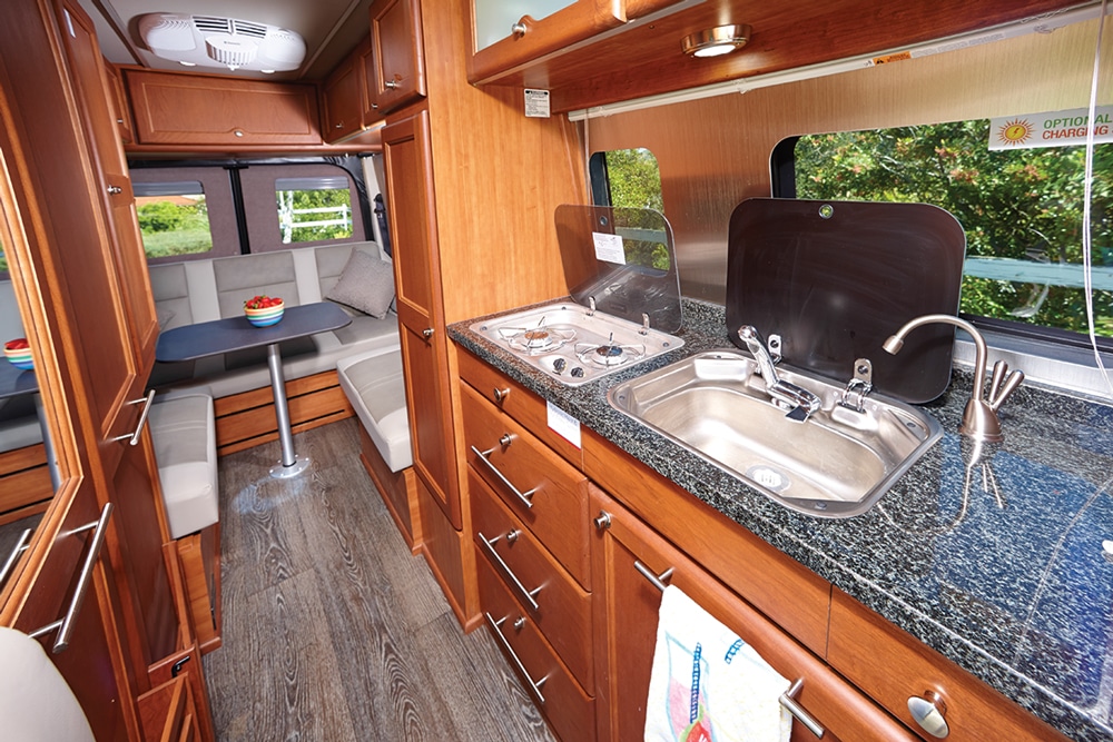The galley offers ample storage and is highlighted by a granite countertop with flush-mounted glass covers for the two-burner cooktop and sink.