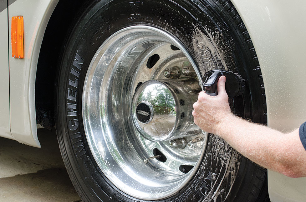 Man scrubbing RV tire with cleaner