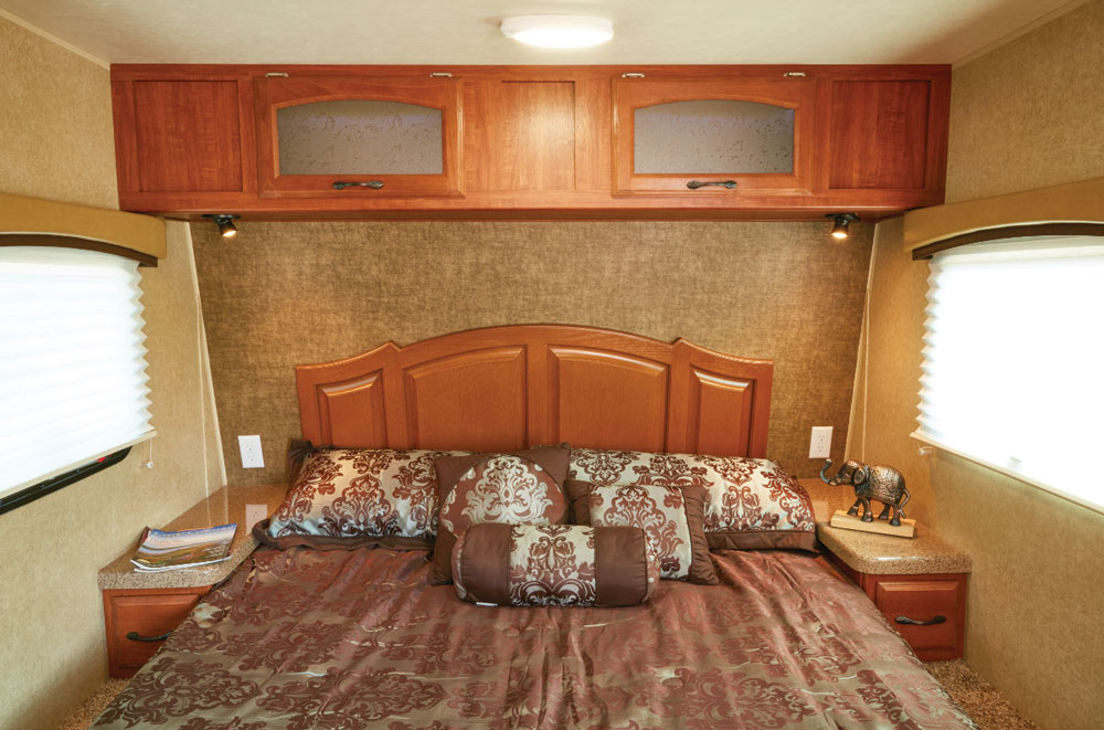 Overhead cabinets in Concord Cherry with Glacier Glass fronts and LED backlighting add a homey, inviting feel at night. The headboard tips slightly forward to follow the contour of the front cap, accenting a comfortable 60-by-74-inch pillow-top mattress.