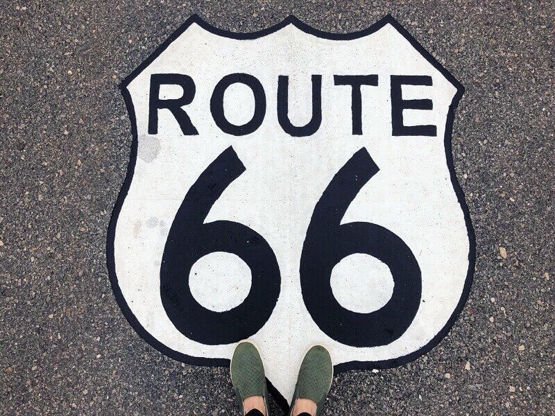 Route 66 painted sign on road with person's feet at bottom 